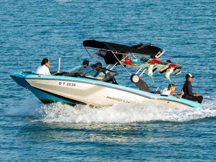 Вейк-катер MasterCraft NXT 20 с гостями на борту поднимает волну на синей воде